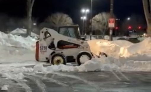 Bobcat removing snow from a parking lot.