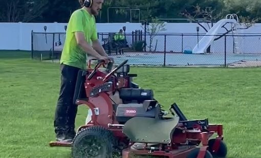 Landscape professional mowing a large backyard.